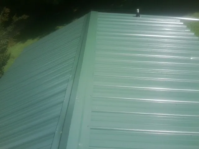 New green metal panels meeting at the ridge of a roof — Flat Roof Repair work by our crew in Avalon